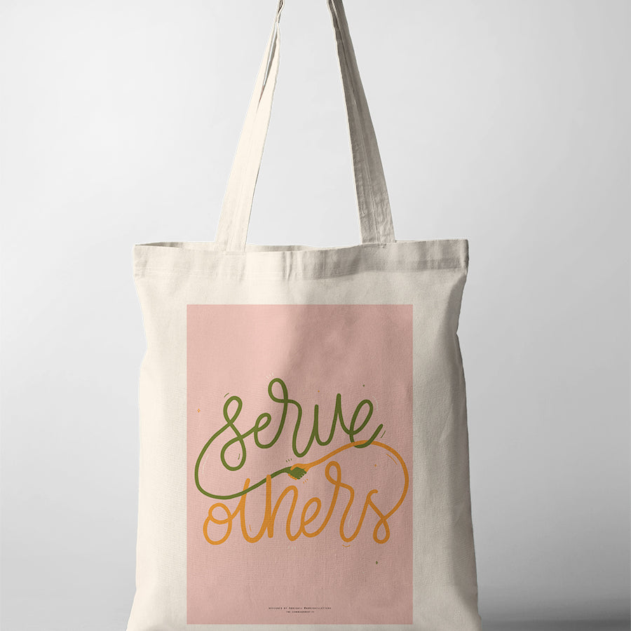 Christian tote bag featuring “Serve others” with hand-lettered text and a small handshake illustration