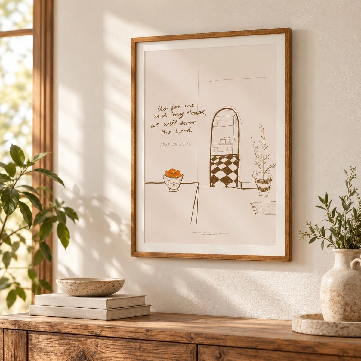 A framed minimalist line art poster with the script "As for me and my house, we will serve the Lord" hangs on a wall above a rustic wooden console table in a sunlit room.