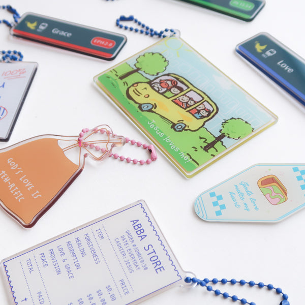 Singapore-inspired Christian acrylic keychain collection featuring Jesus Loves Me transport card, Grace and Love MRT sign designs, Abba Store receipt, and faith-filled reminders