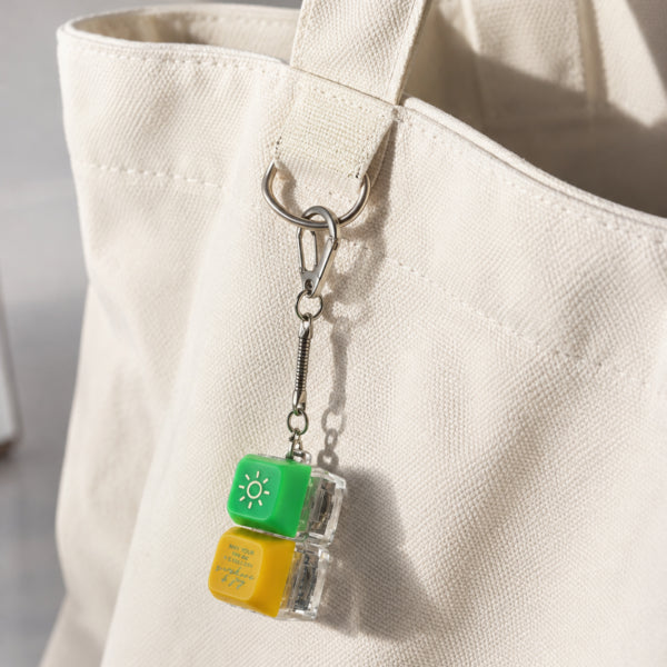 Sunshine and Joy keycap keychain clipped to a cream canvas tote bag