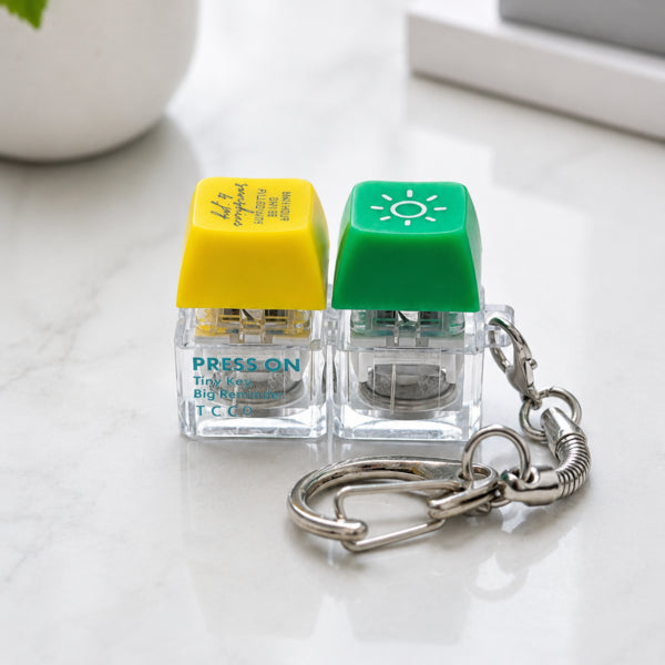 Close-up of the green sun and yellow Sunshine and Joy keycaps with silver keyring