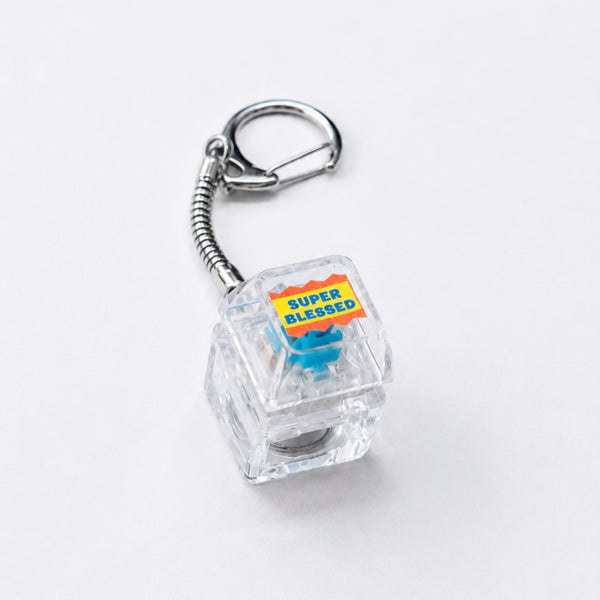 Super Blessed clear light-up keycap keychain with silver clasp on a white background