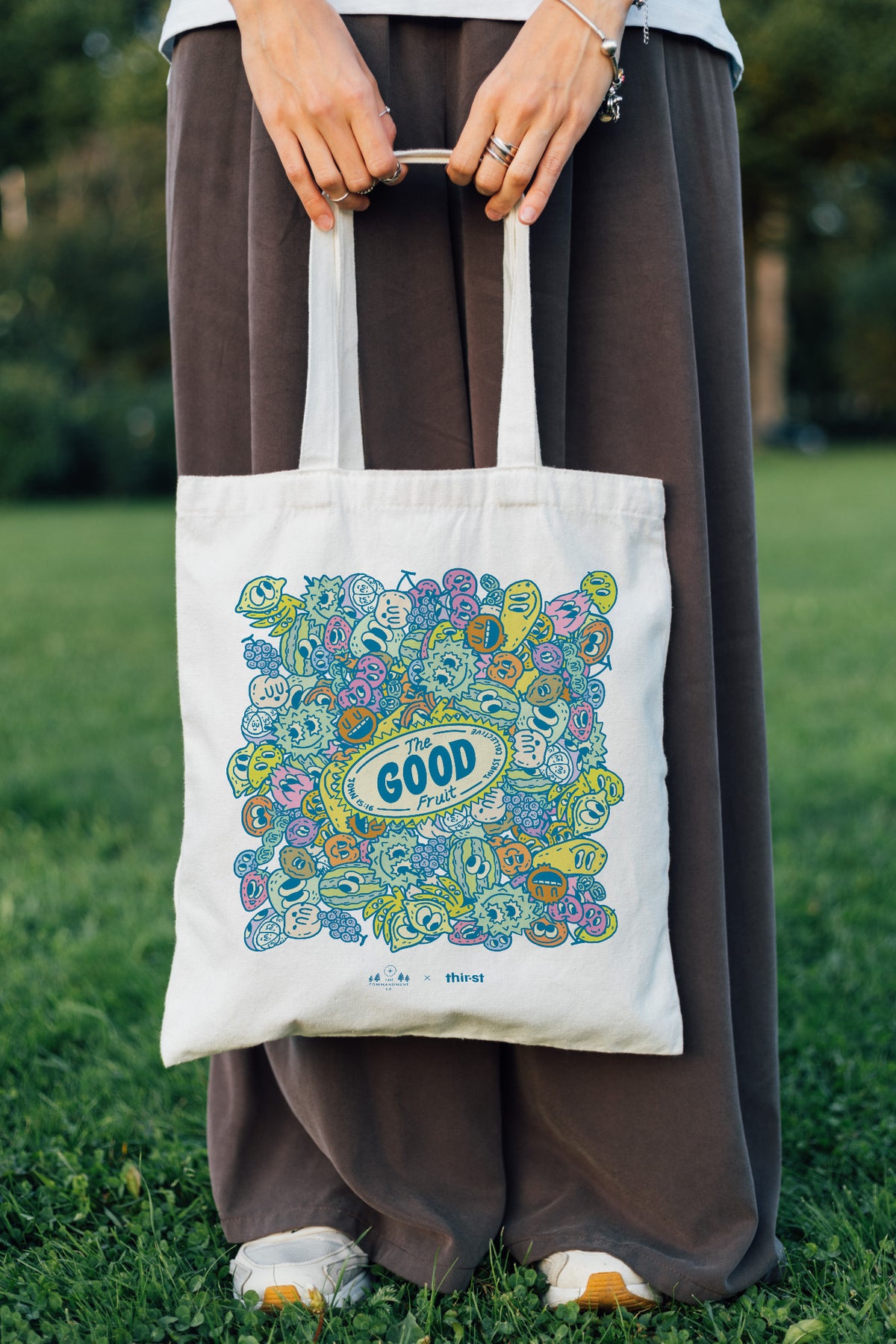 Person carrying The Good Fruit coloured tote bag outdoors