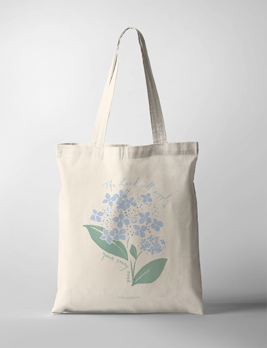 Neutral canvas tote bag featuring a delicate blue hydrangea illustration and the uplifting message "The Lord will supply your every need," inspiring simple happiness and faith-filled encouragement.