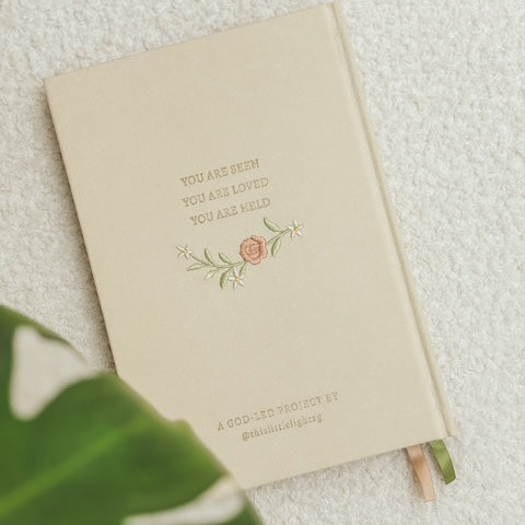 Back cover of This Little Light prayer journal with “You are seen, you are loved, you are held” text and floral embroidery