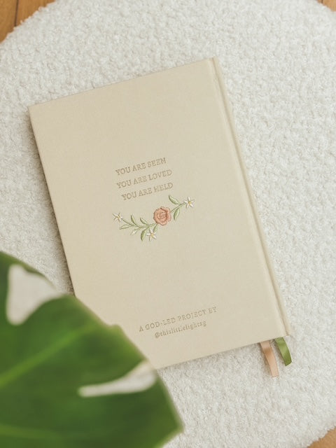Back cover of This Little Light prayer journal with “You are seen, you are loved, you are held” text and floral embroidery