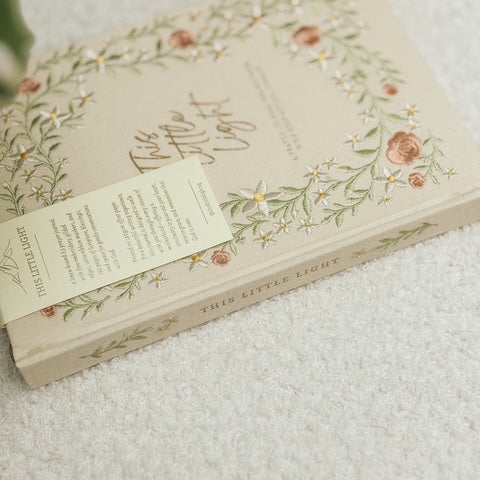 Close-up of This Little Light prayer journal spine with floral embroidery and ribbon bookmarks