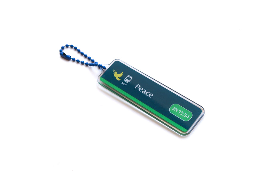 Angled view of Singapore-inspired Train Station Peace acrylic keychain with John 13:34