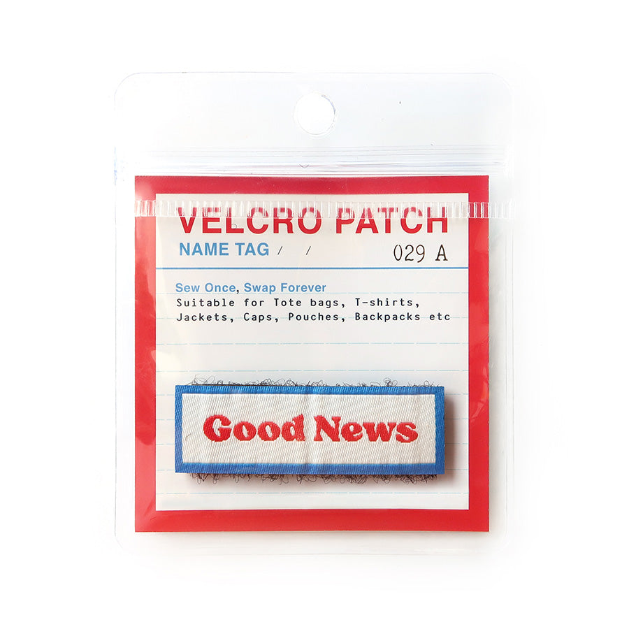 Velcro tag with 'Good News' in red text on a white background, bordered in blue; a Christian-inspired accessory for apparel and bags.