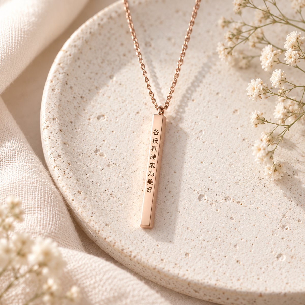 Rose gold personalised vertical bar necklace displayed on a neutral ceramic tray