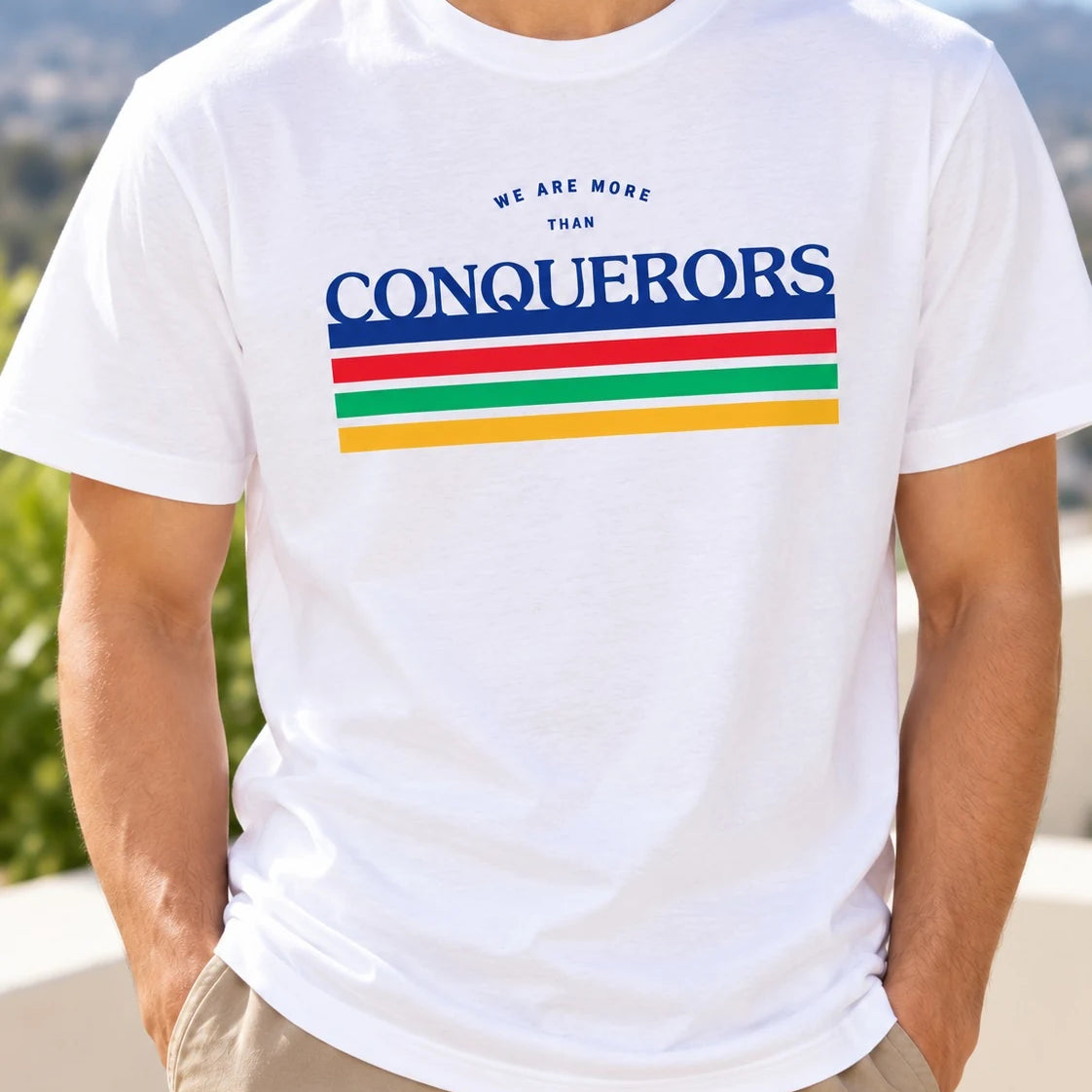 Lifestyle photograph of a man wearing the white We Are More Than Conquerors Christian T-shirt.
