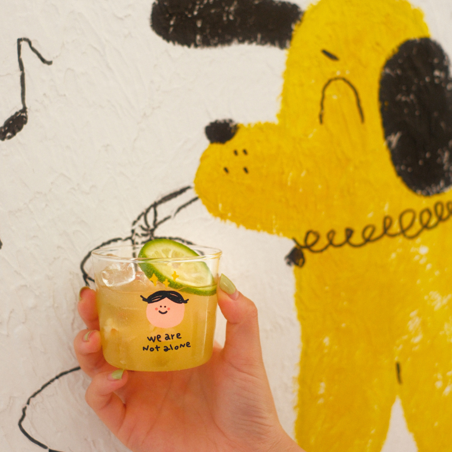 Glass mini cup with "We are not alone" design, filled with a refreshing drink, symbolizing connection