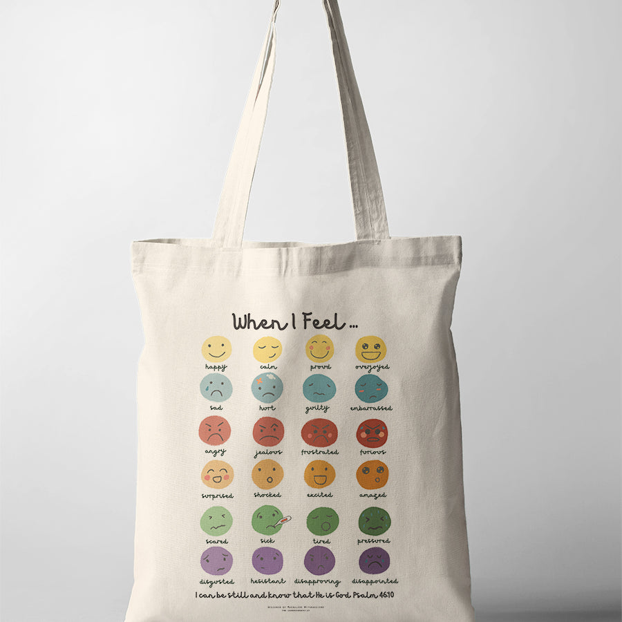 Christian kids tote bag featuring a feelings chart with illustrated emotions and the verse “Be still and know that He is God” from Psalm 46:10.