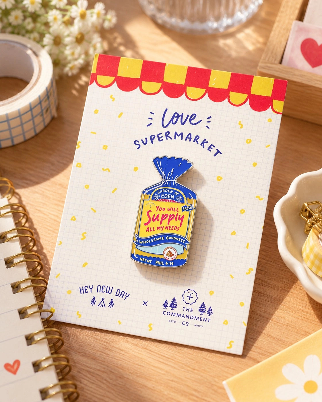 Wholesome Bread Pack LOVE SUPERMARKET Christian enamel pin on illustrated backing card beside a journal and stationery.