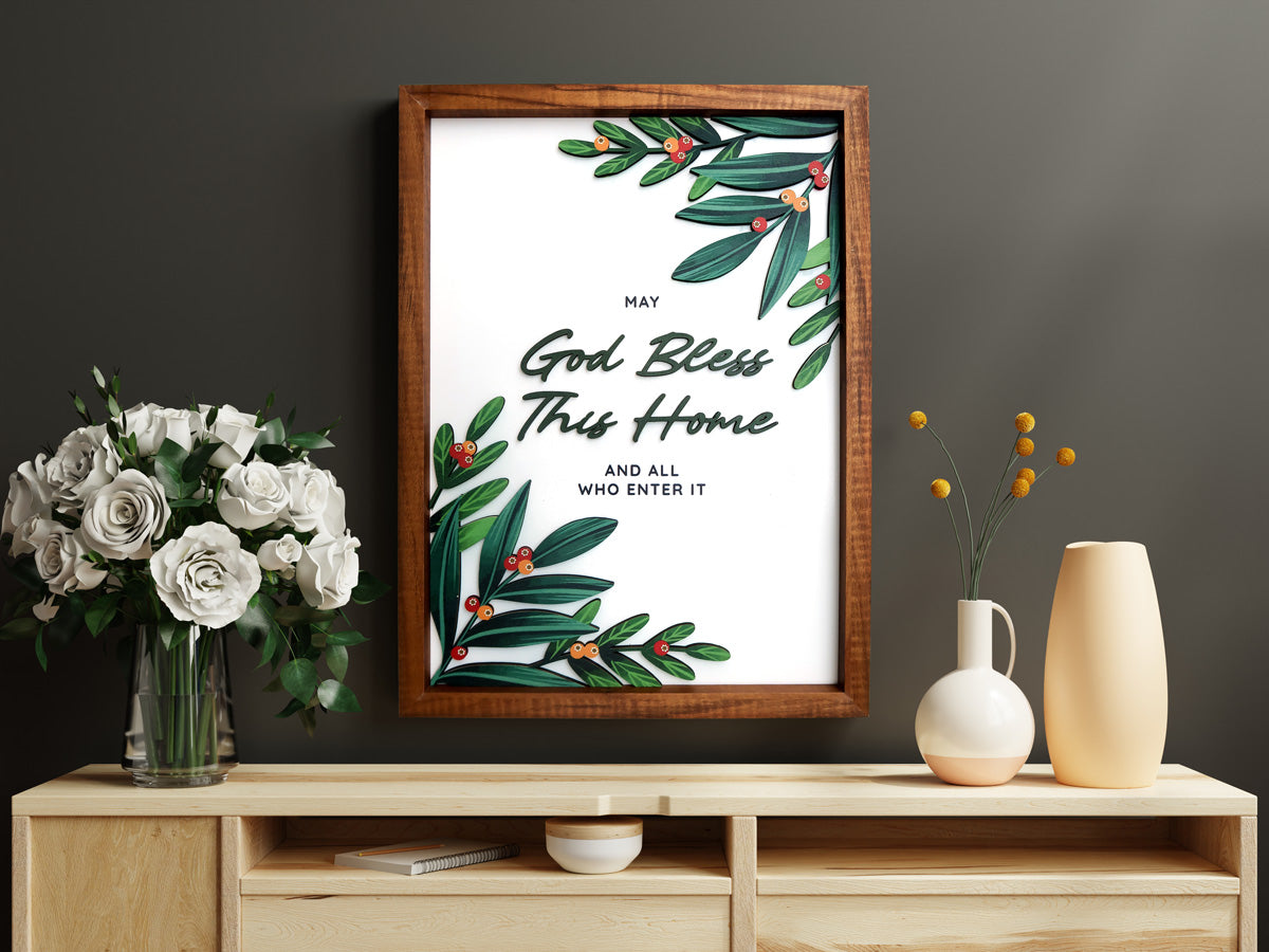 A beautifully styled wooden poster with the phrase "God Bless This Home and All Who Enter It," displayed on a wooden console table with a vase of white flowers and minimalist decor accents in the background.