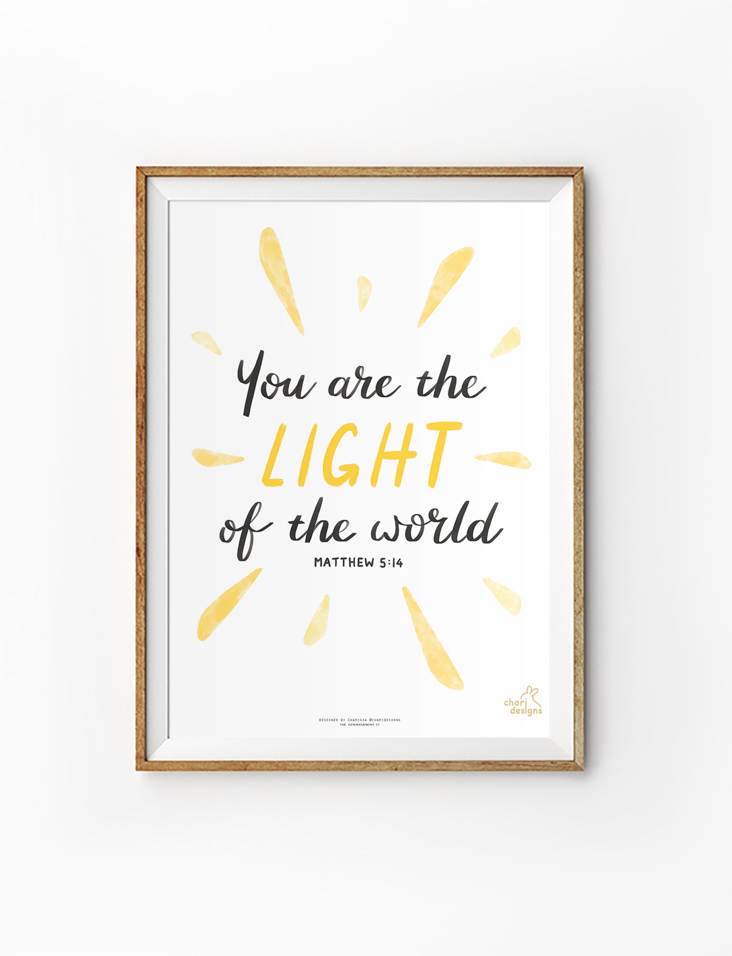 Christian wall art print featuring the Bible verse “You are the light of the world” Matthew 5:14 with yellow sunburst illustration, collaboration with Chari Designs.