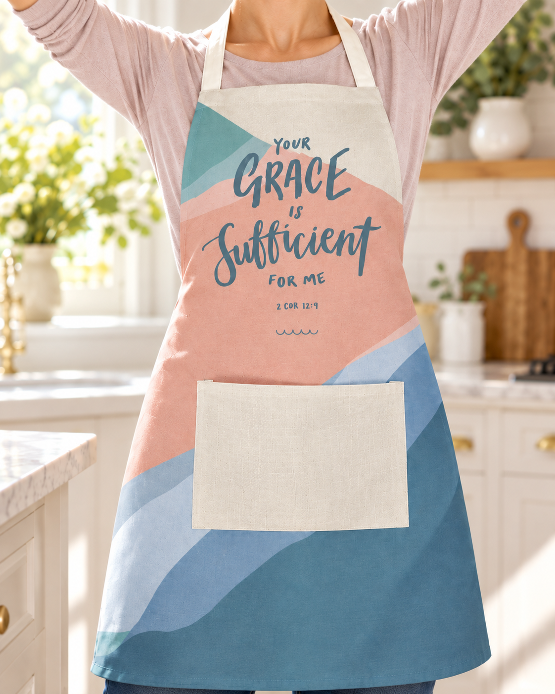 Your Grace Is Sufficient Christian apron worn in a bright kitchen with arms raised.