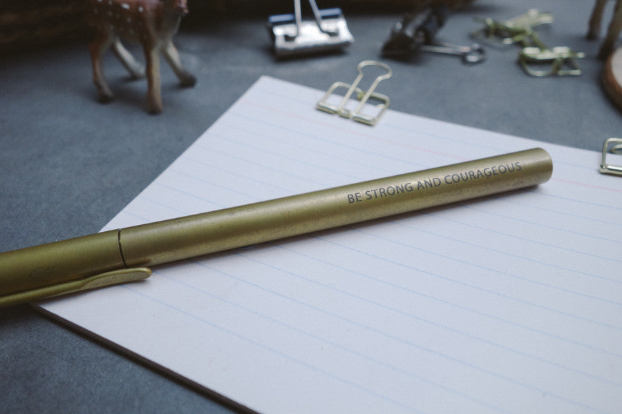 Brass pen barrel with the message 'be strong and courageous'.