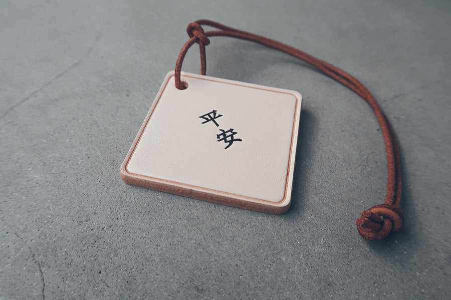 Leather car charm engraved with Ping An for vehicle décor.