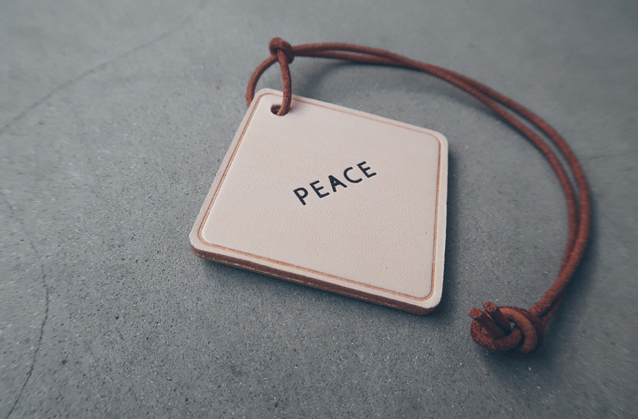 Leather car charm engraved with the word Peace.