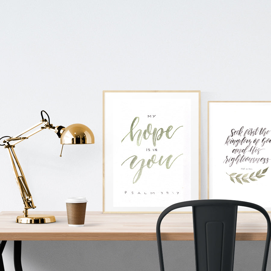 A3 beautiful calligraphy poster placed standing next to a smaller A4 sized calligraphy poster on a wooden table. Modern home interior design ideas.