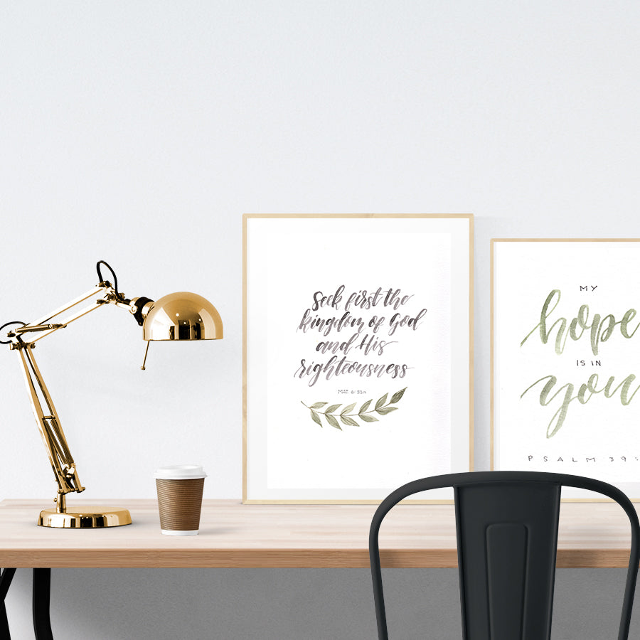 A3 beautiful calligraphy poster placed standing next to a smaller A4 sized calligraphy poster on a wooden table. Modern home interior design ideas.