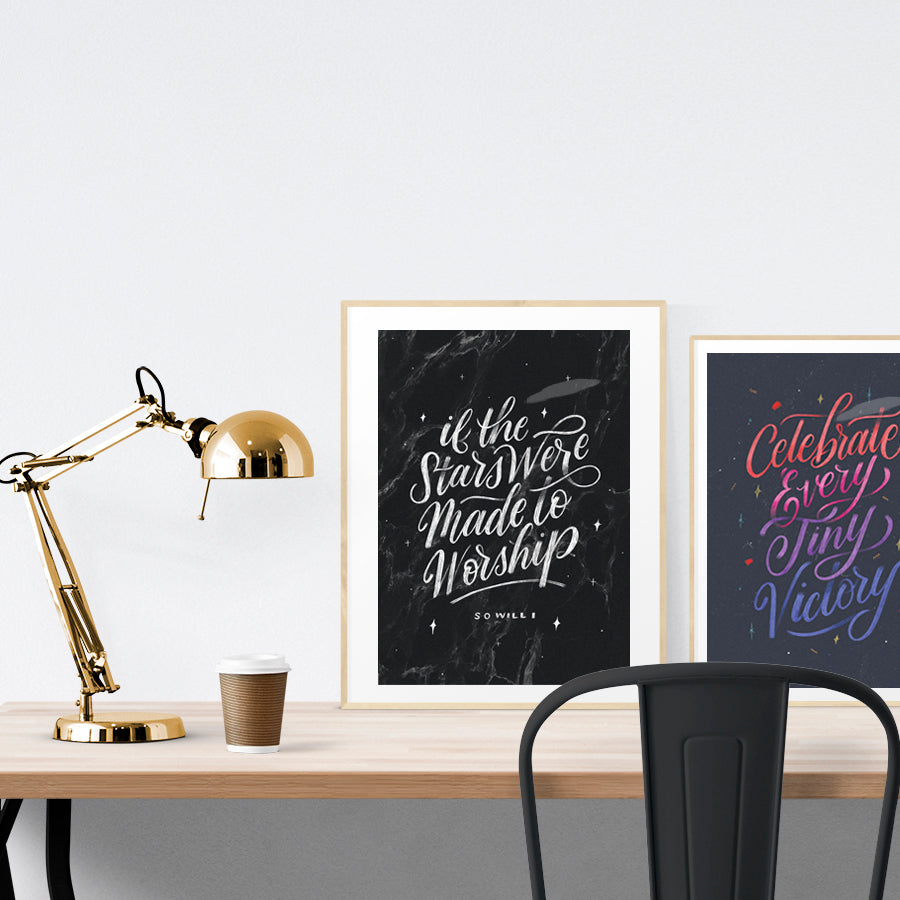 A3 beautiful calligraphy poster placed standing next to a smaller A4 sized calligraphy poster on a wooden table. Minimalistic home interior design ideas.