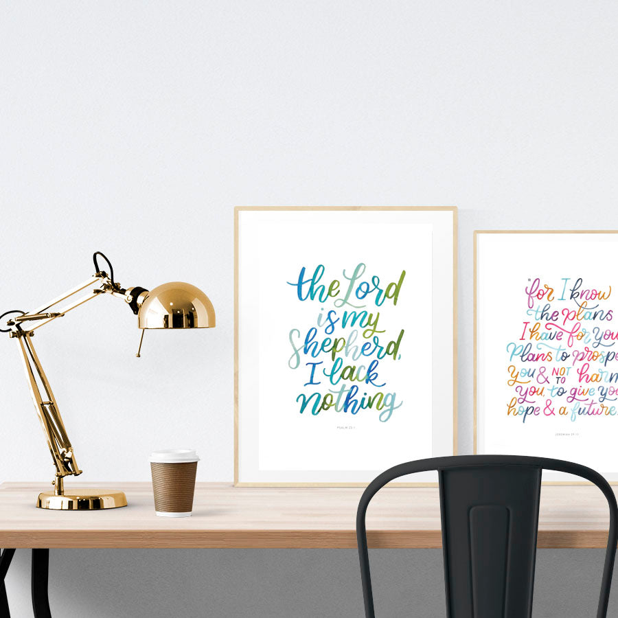 A3 beautiful calligraphy poster placed standing next to a smaller A4 sized calligraphy poster on a wooden table. Modern home interior design ideas.