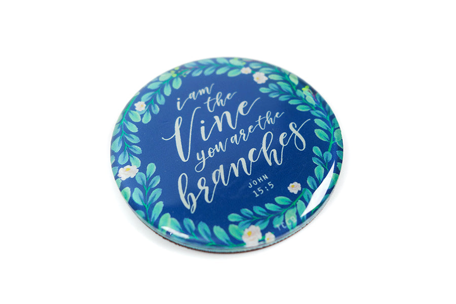 Close up of 5.5 cm diameter circular Acrylic fridge magnet with bible verse “I am the vine and you are the branches” on foliage background.