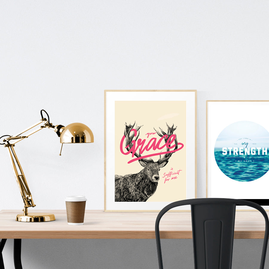 A3 beautiful calligraphy poster placed standing next to a smaller A4 sized calligraphy poster on a wooden table. Modern Christian home interior design ideas.