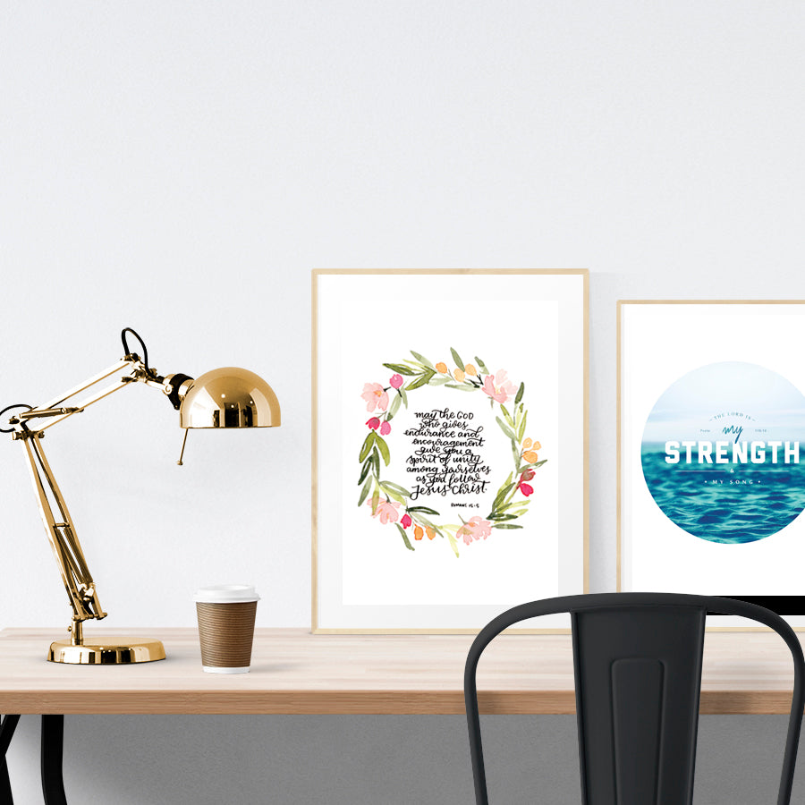 A3 beautiful calligraphy poster placed standing next to a smaller A4 sized calligraphy poster on a wooden table. Rustic home interior design ideas.