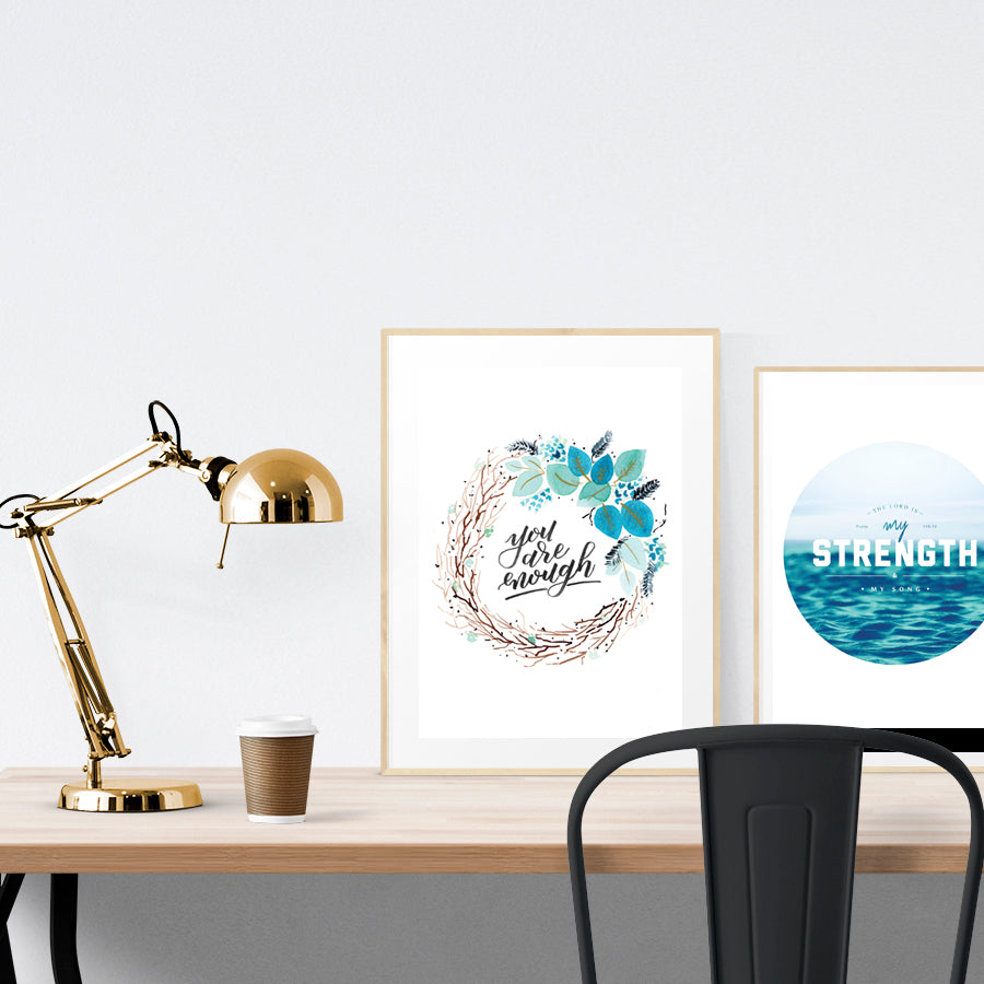 A3 beautiful calligraphy poster placed standing next to a smaller A4 sized calligraphy poster on a wooden table. Modern Christian home interior design ideas.