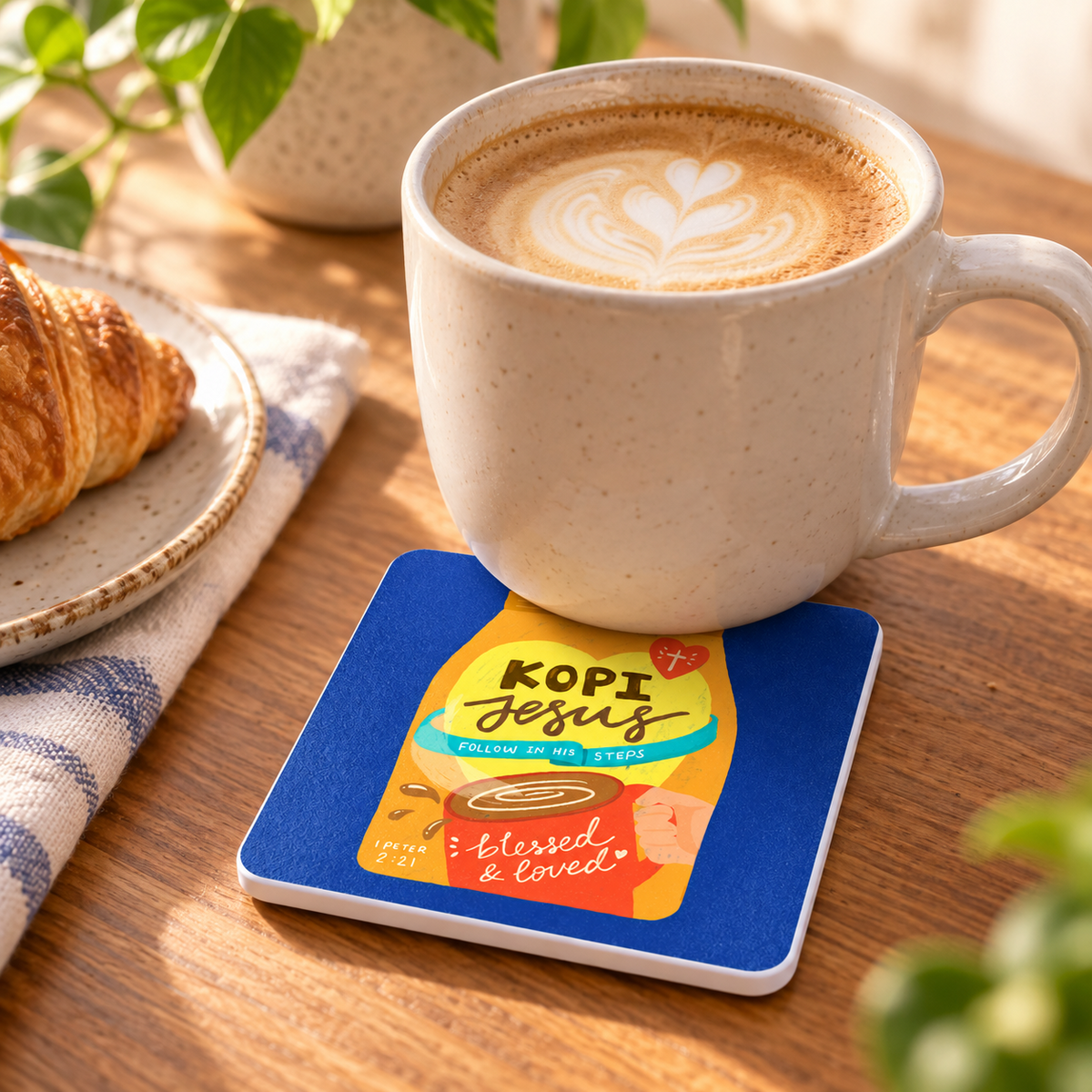 Kopi Jesus Love Supermarket Christian coaster with white sides styled beneath a latte on a warm wooden table