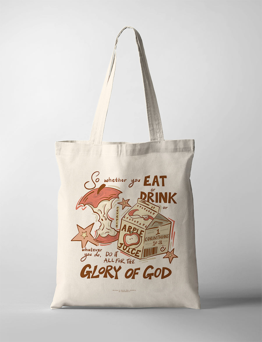 Canvas Christian tote bag with playful apple and juice illustration and the verse “Do it all for the glory of God” from 1 Corinthians 10:31