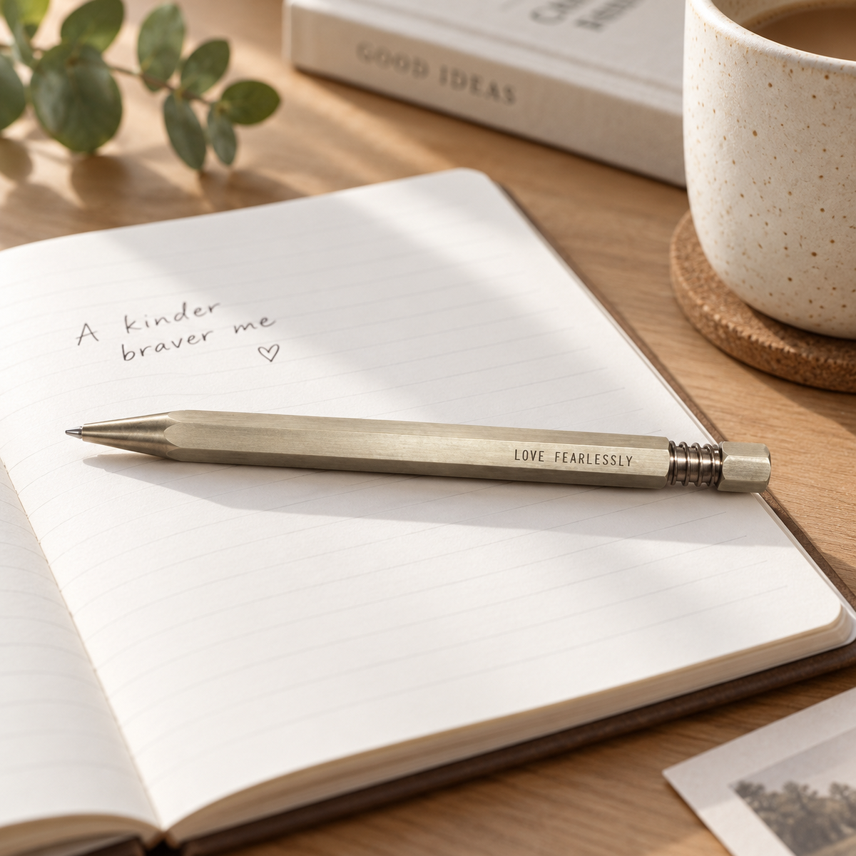 Hex II Classic personalised brass pen engraved Love Fearlessly styled on an open notebook in warm natural light