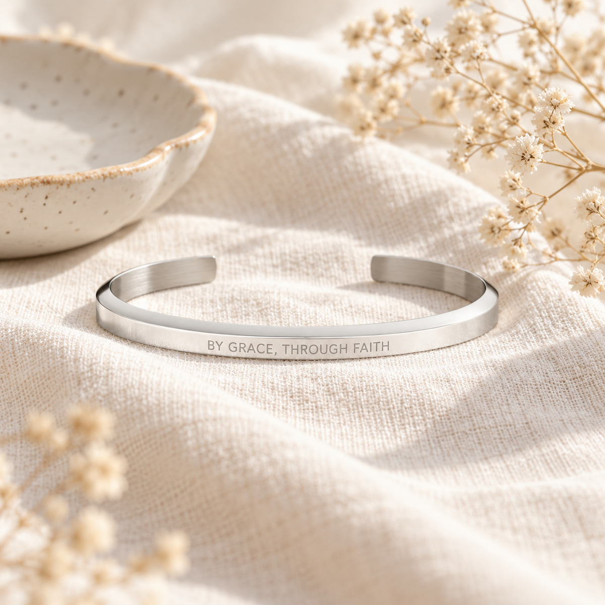 By Grace Through Faith silver Christian verse band styled on soft cream linen with delicate dried flowers in warm natural light