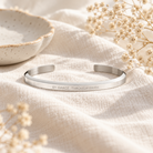 By Grace Through Faith silver Christian verse band styled on soft cream linen with delicate dried flowers in warm natural light