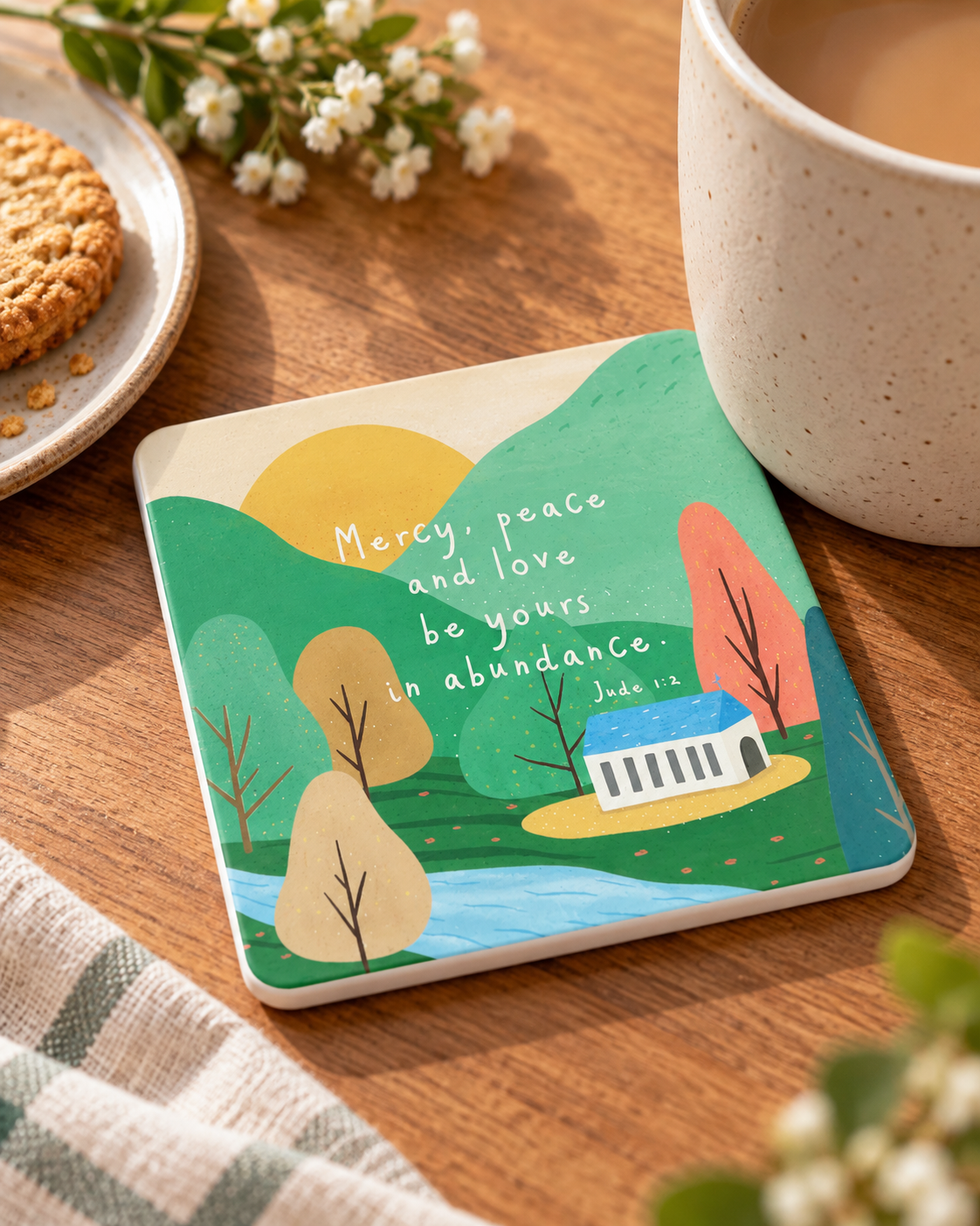 Mercy Peace and Love Jude 1:2 Christian coaster with white sides styled beside coffee on a warm wooden table