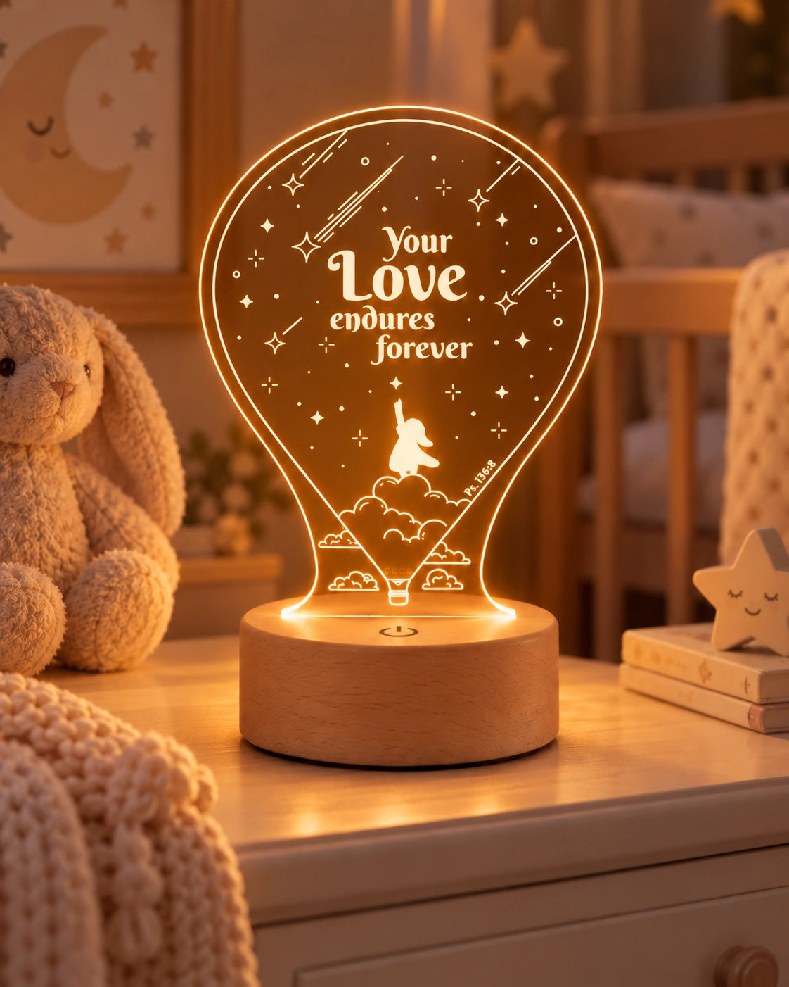 Your Love Endures Forever Psalm 136 night light glowing on a thick wooden base in a warm baby room