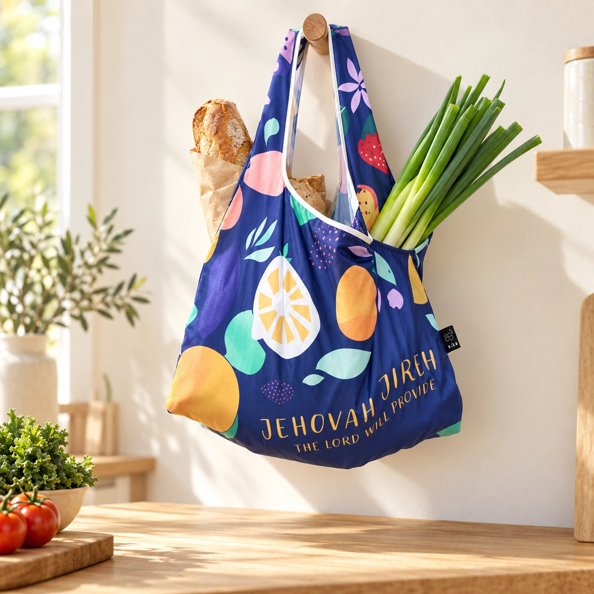 Jehovah Jireh reusable shopping bag filled with groceries and hanging in a sunlit kitchen