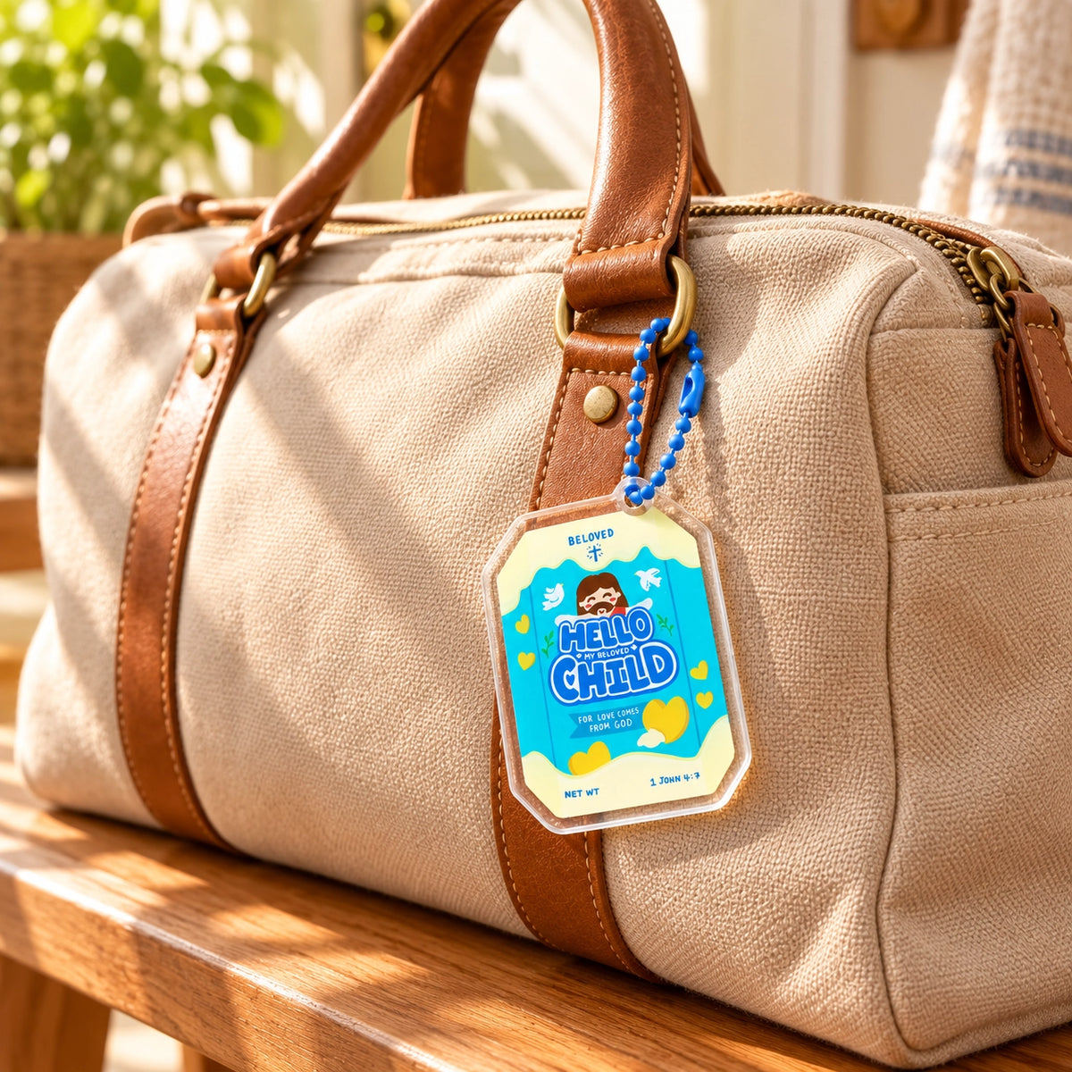 Hello My Beloved Child biscuit acrylic keychain hanging from a beige canvas bag
