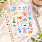 Self Care Everyday Stickers sticker sheet styled with journaling supplies on a sunlit desk.