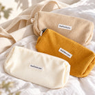 God's Blessings corduroy pencil cases in three colours styled on soft neutral bedding.