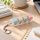 REST four pastel keycap keychain on a wooden desk next to keyboard