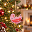 Pink Peace wooden dove Christmas bauble hanging on a warmly lit Christmas tree