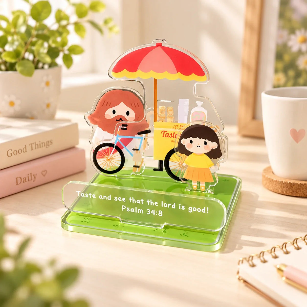 Taste and See ice cream cart acrylic phone stand displayed on a bright desk with a plant and books