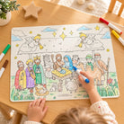 Child colouring the Nativity of Jesus mat with pens on a wooden table