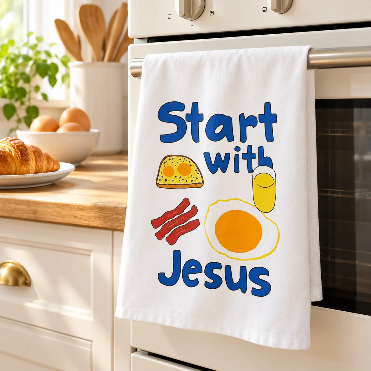 Start With Jesus tea towel hanging over an oven handle in a sunlit kitchen