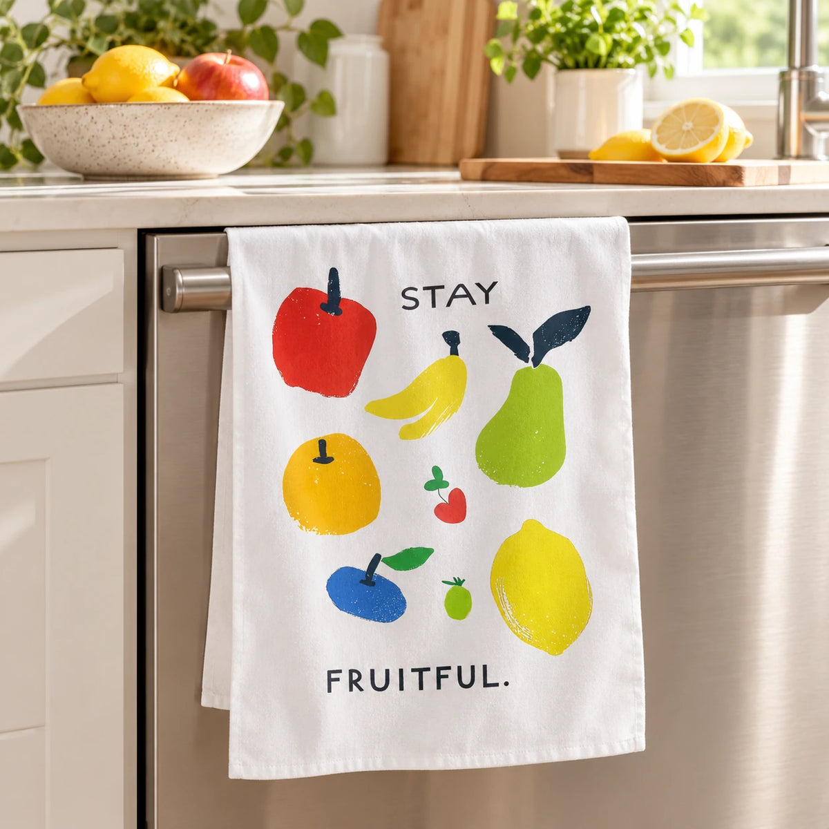 Stay Fruitful fruit-print tea towel hanging from a kitchen oven handle