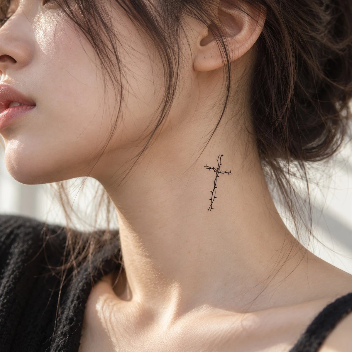 Delicate black Christian cross temporary tattoo applied to the side of a woman's neck